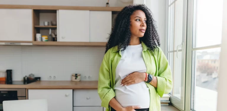young pregnant woman standing in the kitchen